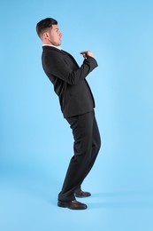 Photo of Emotional man in suit pointing at himself on light blue background