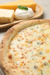 Delicious cheese pizza and different kinds of cheese on table, closeup