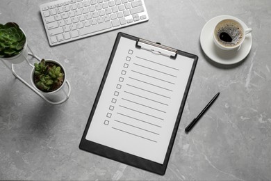 Clipboard with checkboxes, cup of coffee, plants and computer keyboard on light grey table, flat lay. Checklist