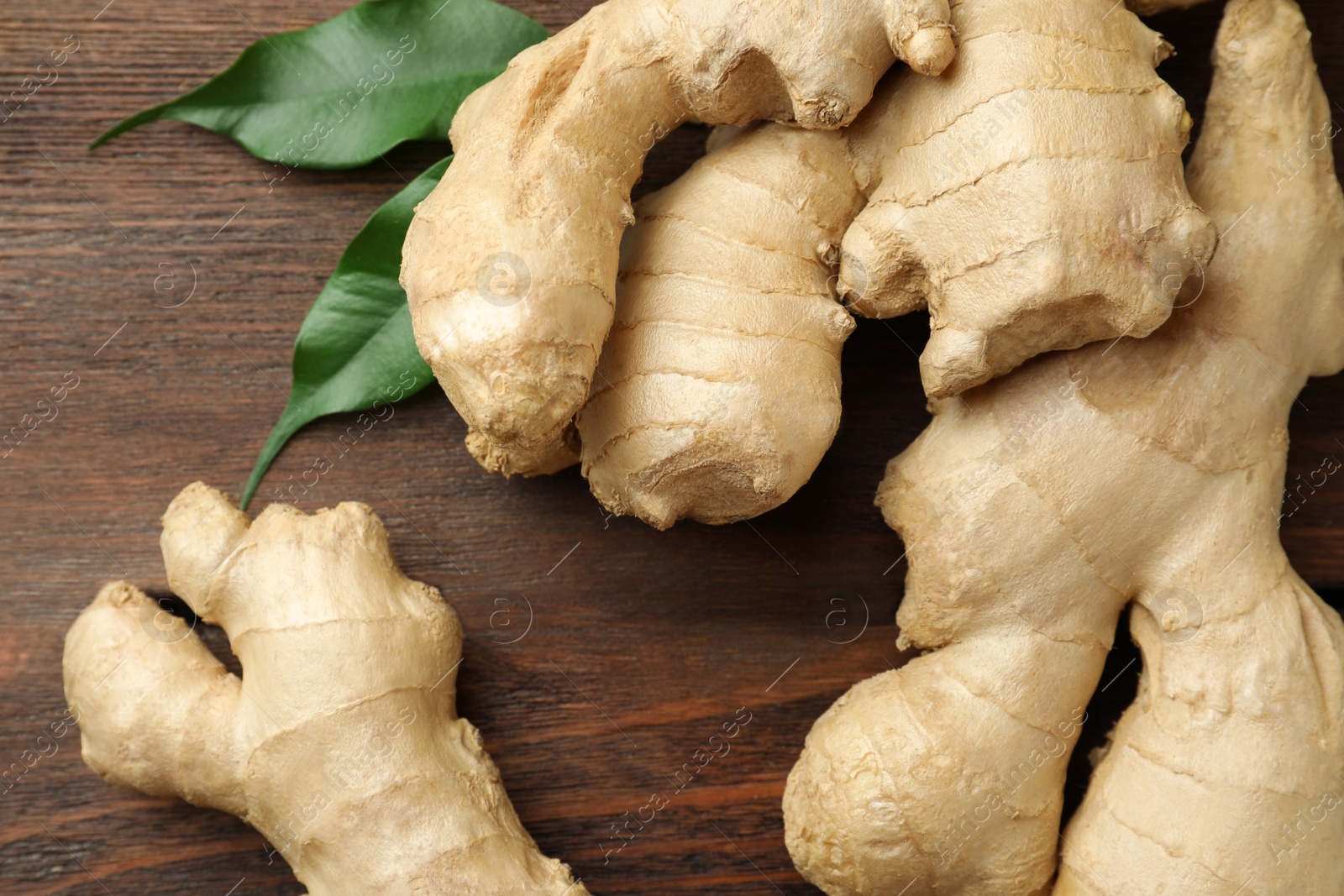 Photo of Fresh ginger with leaves on wooden table, closeup