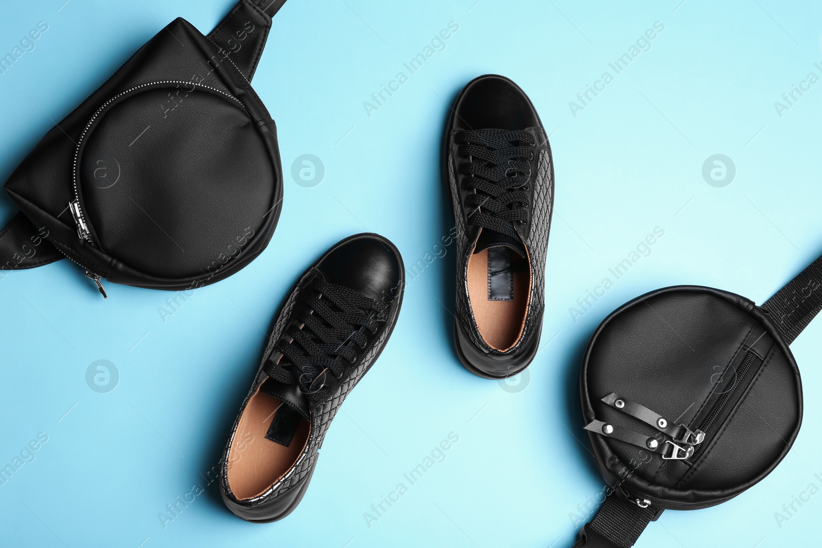 Photo of Flat lay composition of stylish shoes and bum bags on color background