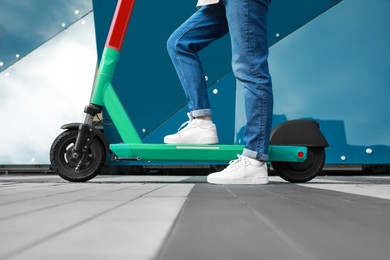 Photo of Woman with modern electric kick scooter on city street, closeup