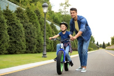 Dad teaching son to ride bicycle outdoors