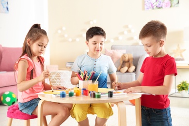 Photo of Cute little children painting at table in playing room