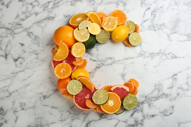 Photo of Letter C made with citrus fruits on marble table as vitamin representation, flat lay