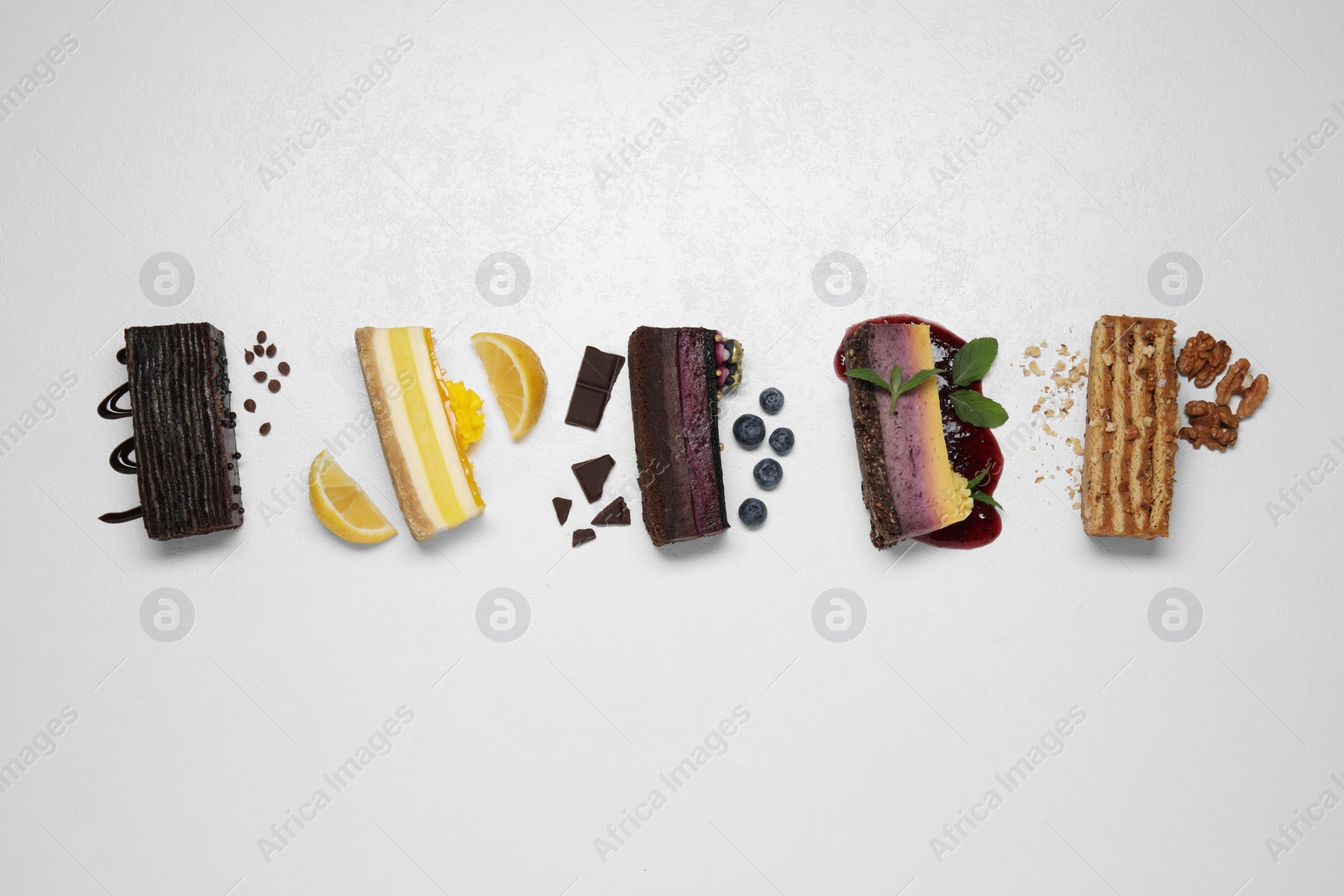 Photo of Flat lay composition with different tasty cakes on light table