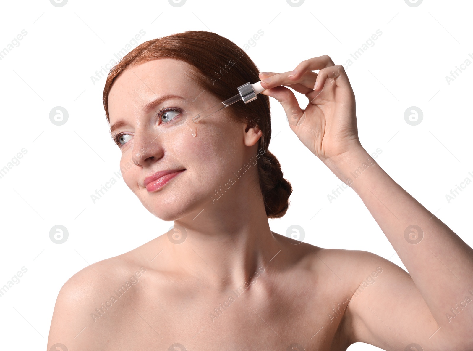 Photo of Beautiful woman with freckles applying cosmetic serum onto her face on white background