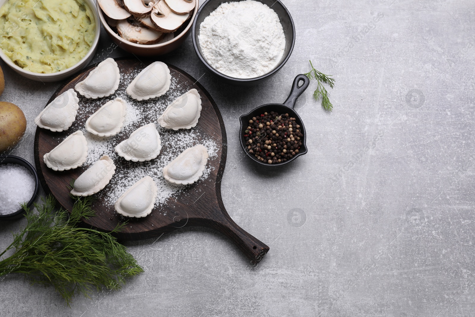 Photo of Raw dumplings (varenyky) and ingredients on grey table, flat lay. Space for text