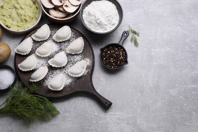 Raw dumplings (varenyky) and ingredients on grey table, flat lay. Space for text