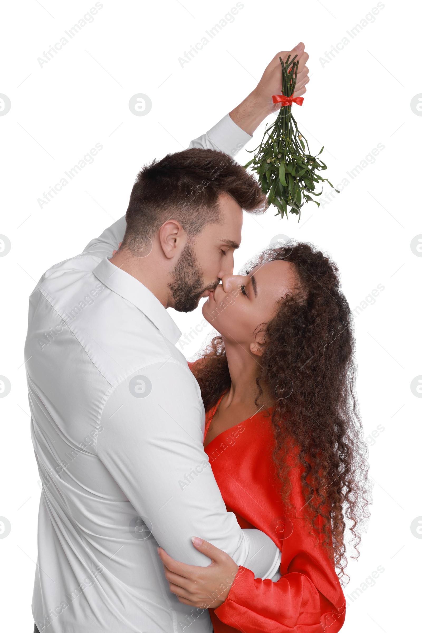 Photo of Happy couple kissing under mistletoe bunch on white background