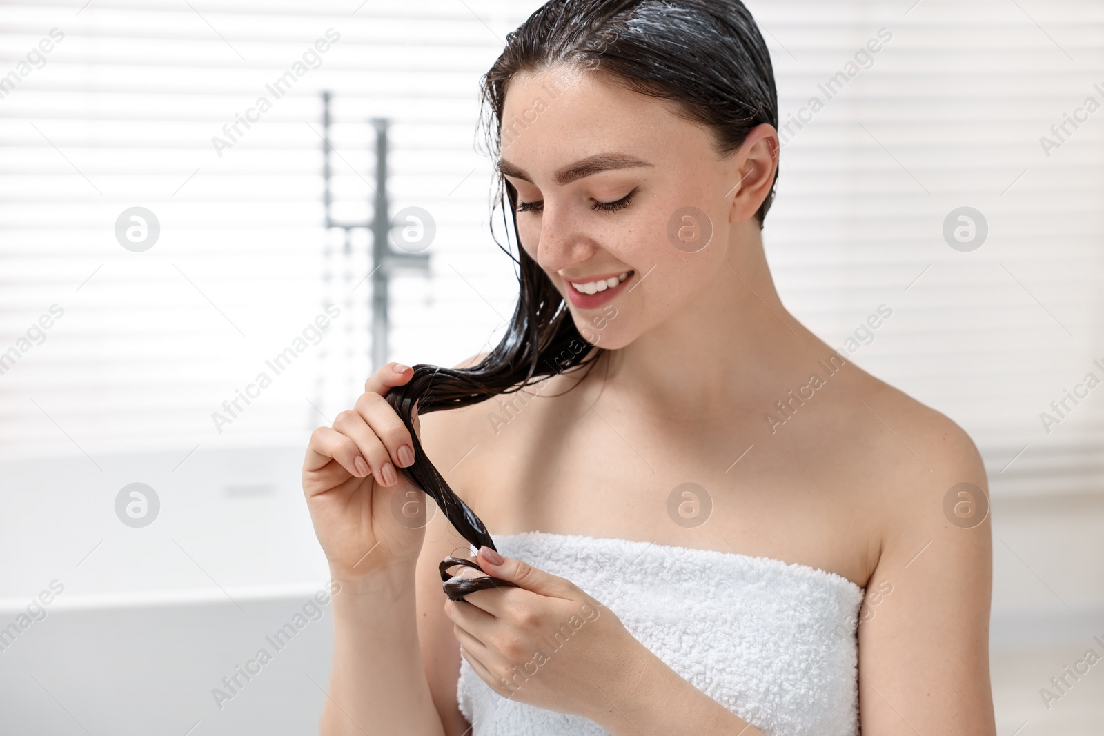 Photo of Smiling woman with applied hair mask in bathroom