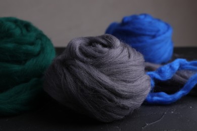 Photo of Colorful felting wool on dark textured table, closeup