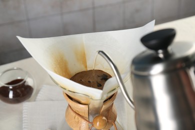 Making drip coffee. Pouring hot water into chemex coffeemaker with paper filter at table, closeup