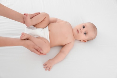 Photo of Mother and her cute child on white bed, above view. Baby massage and exercises