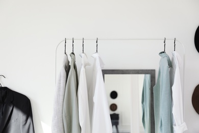 Photo of Rack with stylish clothes near mirror in dressing room