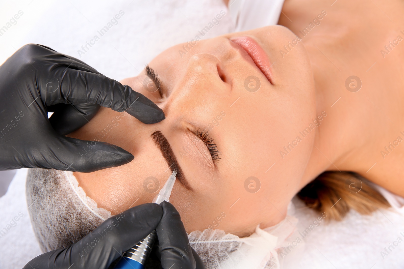 Photo of Young woman undergoing eyebrow correction procedure in salon