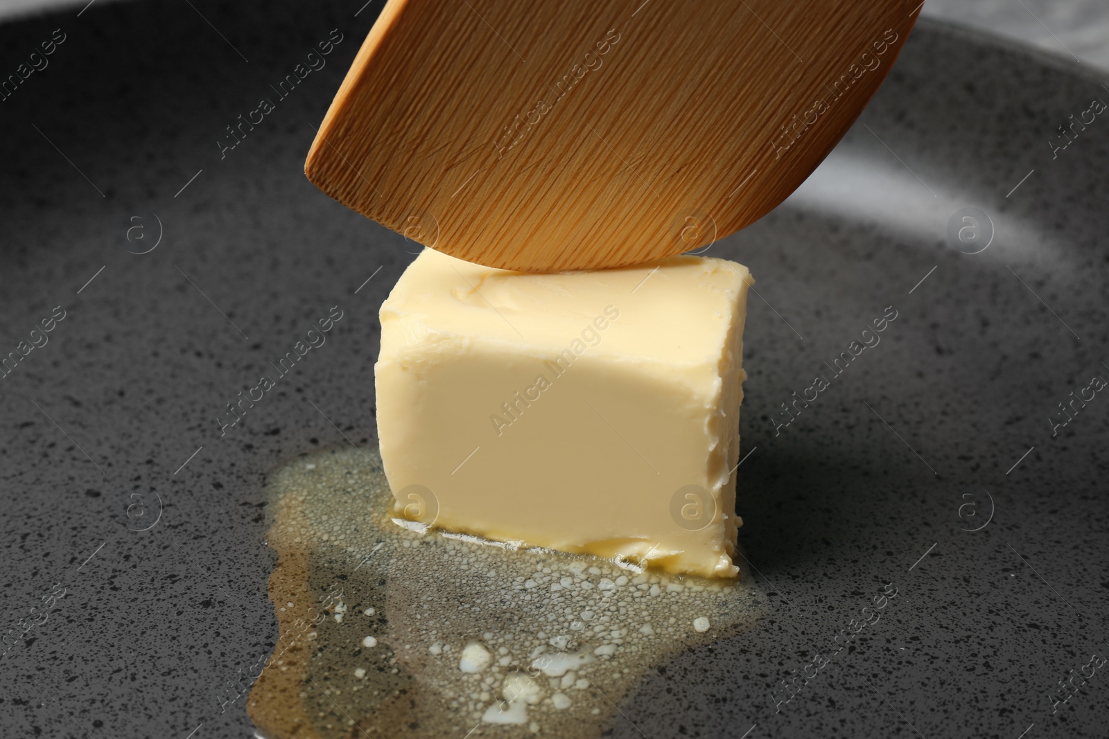 Photo of Frying pan with piece of melting butter and spatula, closeup