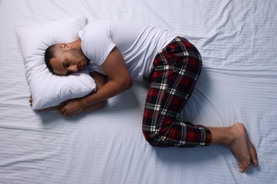Man suffering from insomnia on bed, top view