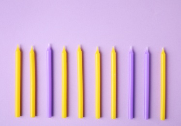 Colorful birthday candles on lilac background, flat lay