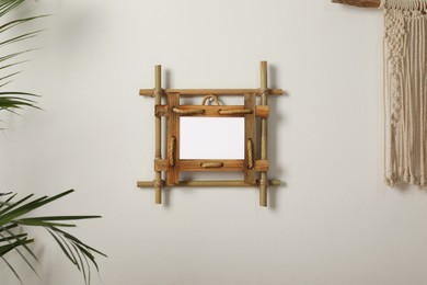 Photo of Empty bamboo frame hanging on white wall indoors