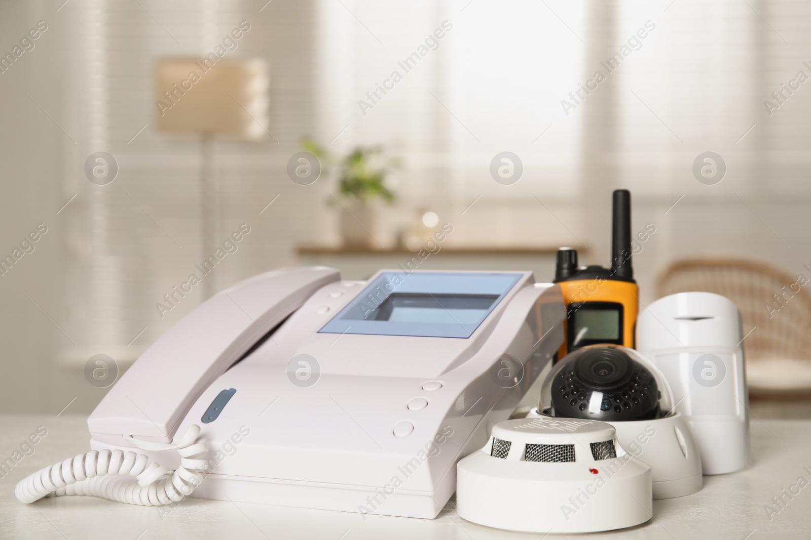Photo of Intercom, CCTV camera, walkie talkie, smoke and movement detectors on white table indoors. Home security system
