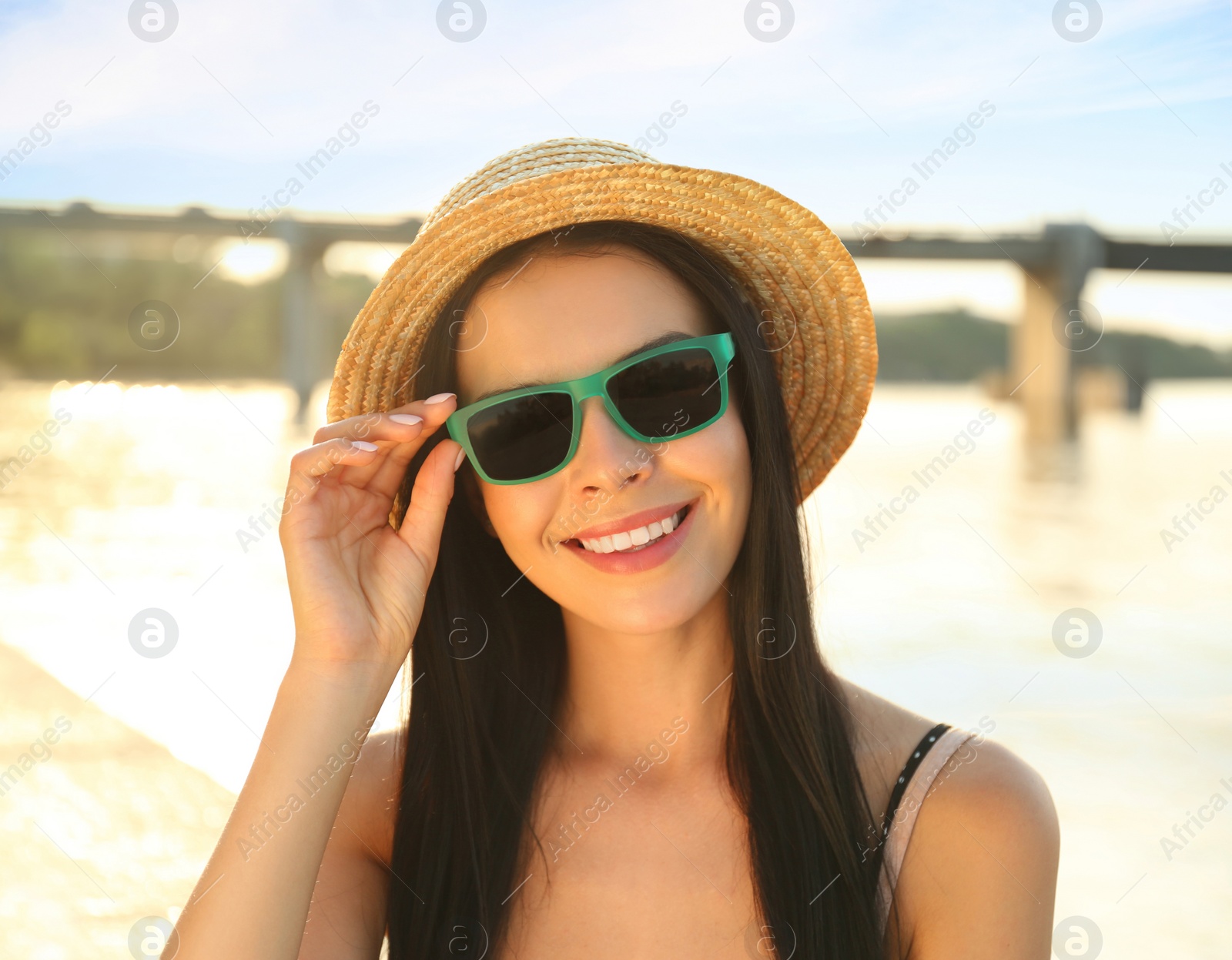 Photo of Beautiful young woman wearing stylish sunglasses near river