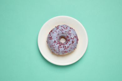 Photo of Delicious glazed donut on turquoise background, top view