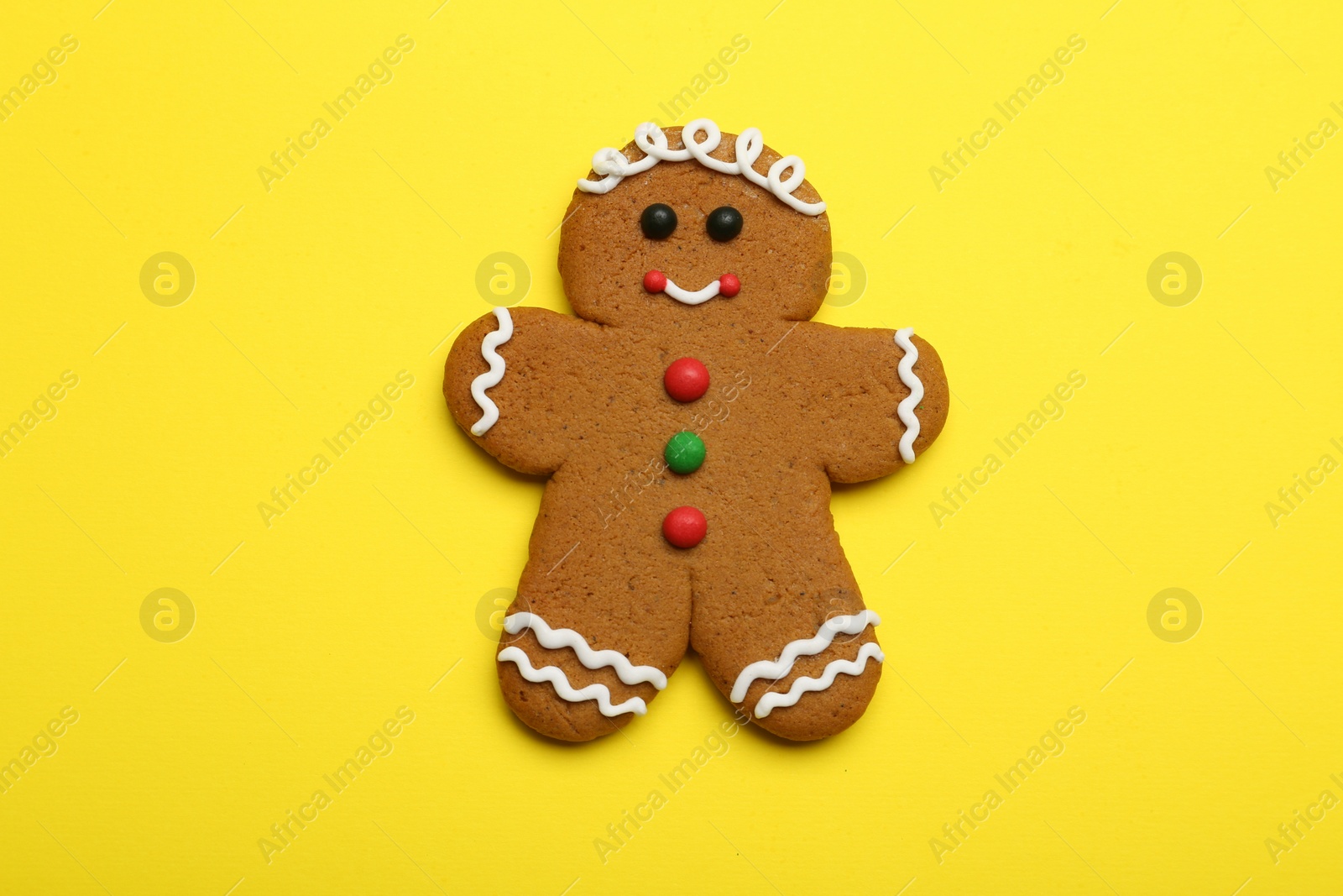 Photo of Gingerbread man on yellow background, top view. Delicious Christmas cookie