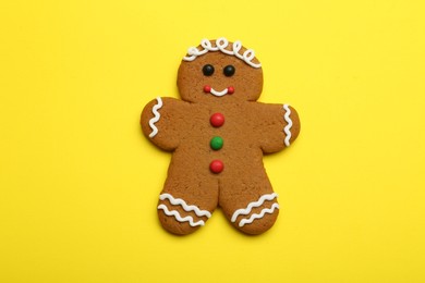 Photo of Gingerbread man on yellow background, top view. Delicious Christmas cookie
