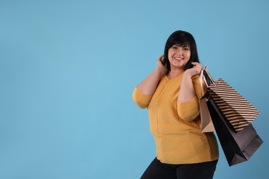 Photo of Beautiful overweight mature woman with shopping bags on turquoise background. Space for text