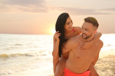 Happy young couple having fun on beach on sunny day