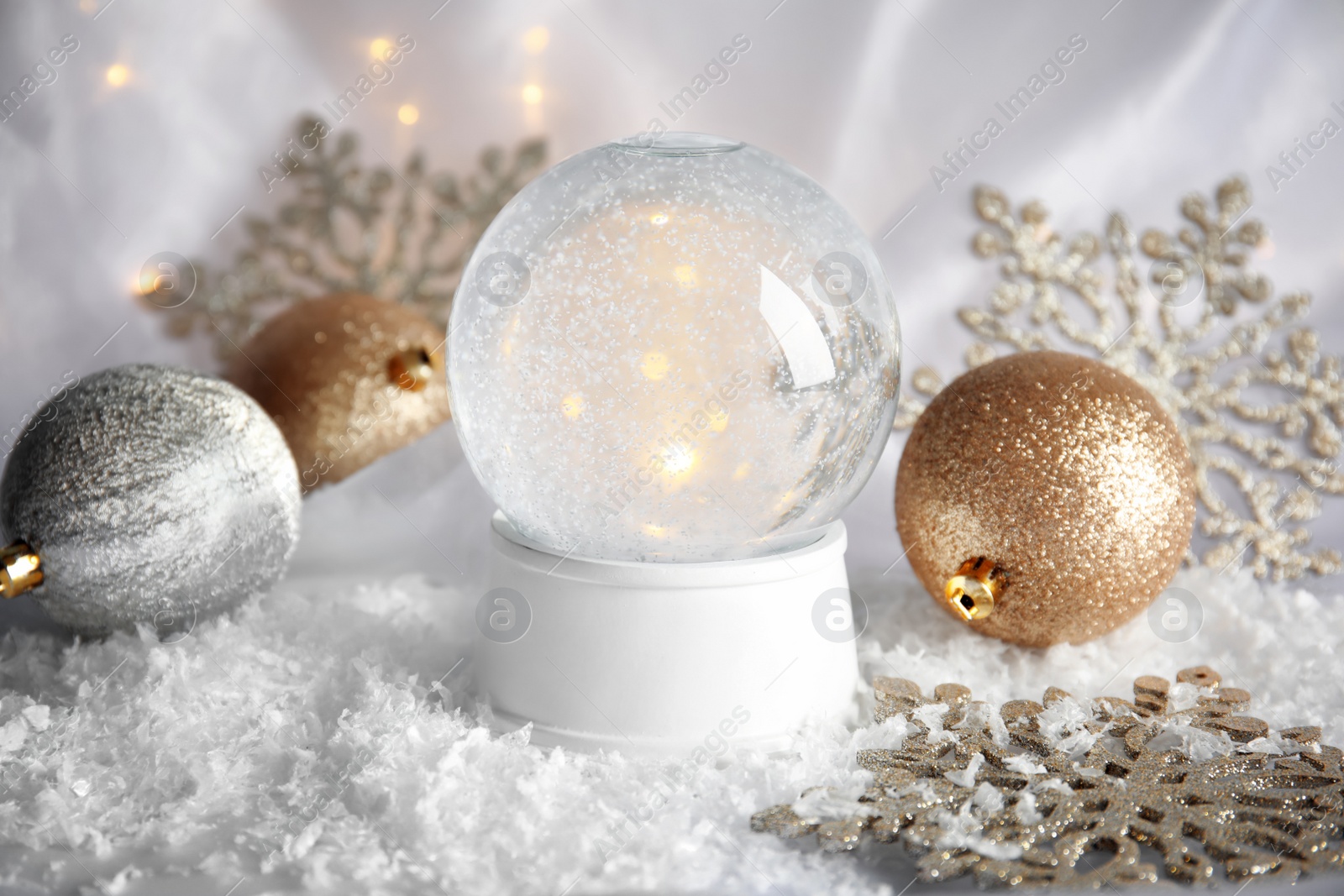 Photo of Magical empty snow globe with Christmas decorations on white fabric