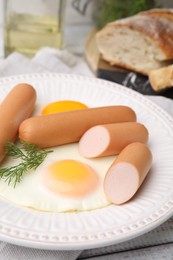Photo of Delicious boiled sausages, fried eggs and dill on table, closeup