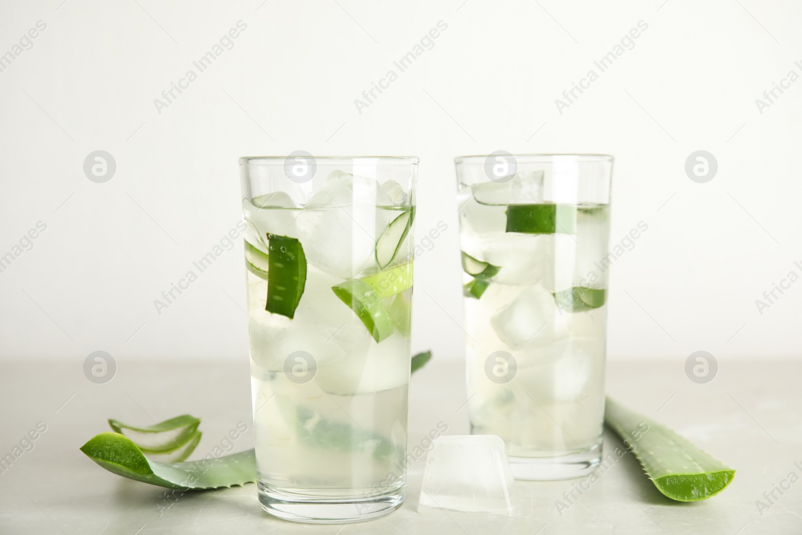 Photo of Fresh aloe drink in glasses and leaves on light table