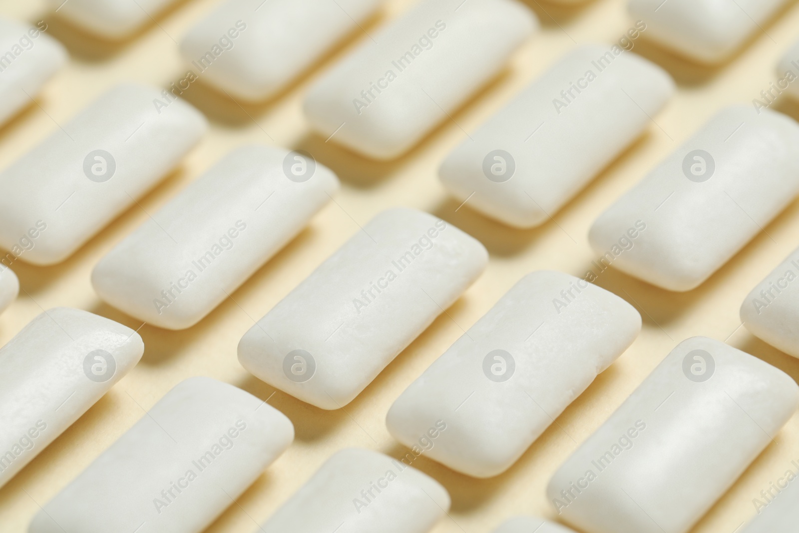 Photo of Tasty white chewing gums on beige background, closeup