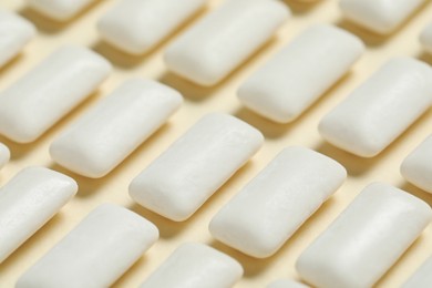 Photo of Tasty white chewing gums on beige background, closeup