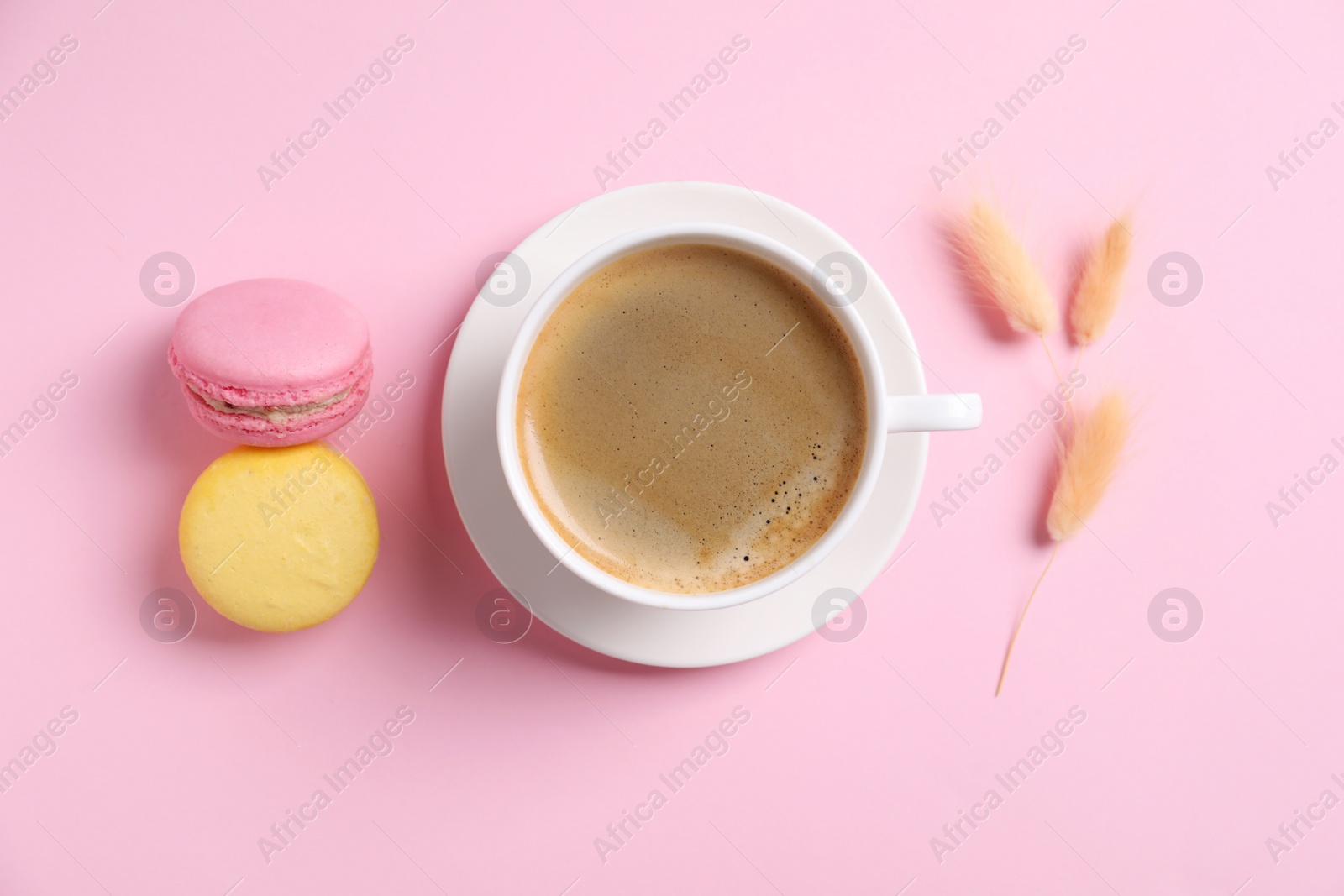 Photo of Aromatic morning coffee and macarons on pink background, flat lay