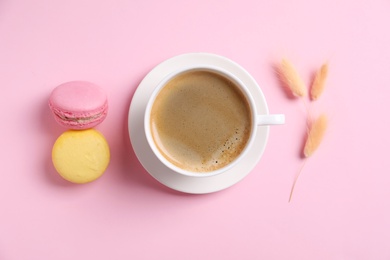 Aromatic morning coffee and macarons on pink background, flat lay