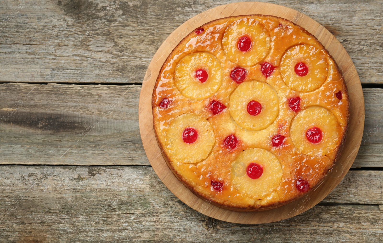 Photo of Tasty pineapple cake with cherries on wooden table, top view. Space for text