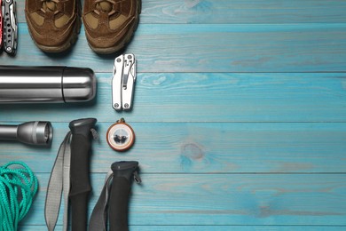 Photo of Flat lay composition with trekking poles and other hiking equipment on light blue wooden background, space for text