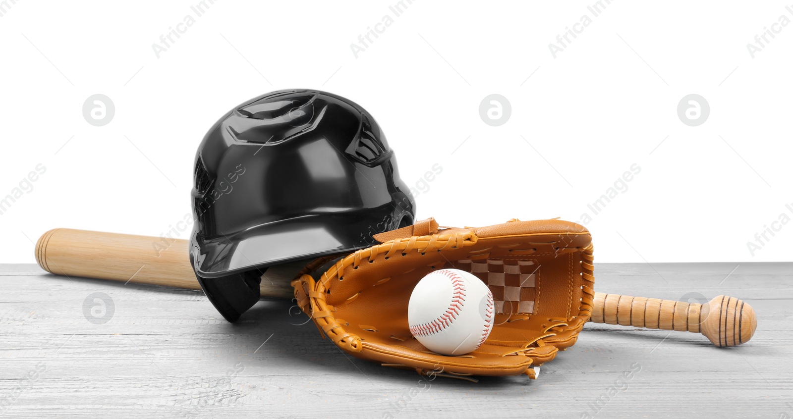 Photo of Baseball glove, bat, ball and batting helmet on light grey wooden table against white background