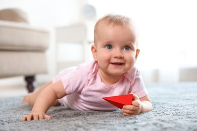Photo of Cute baby girl playing on floor in room