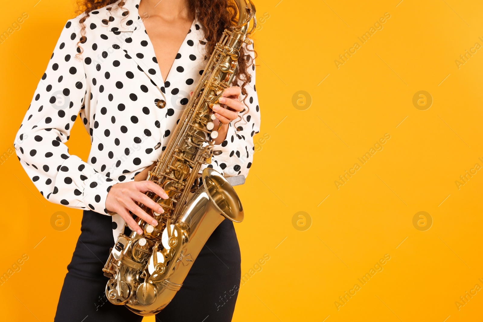 Photo of African American woman with saxophone on yellow background. Space for text