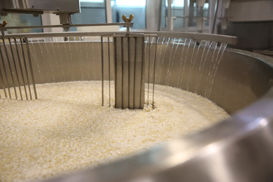 Adding water to curd and whey in tank at cheese factory