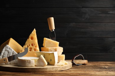 Photo of Different sorts of cheese and knives on wooden table. Space for text