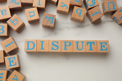 Cubes with word Dispute on white marble table, flat lay