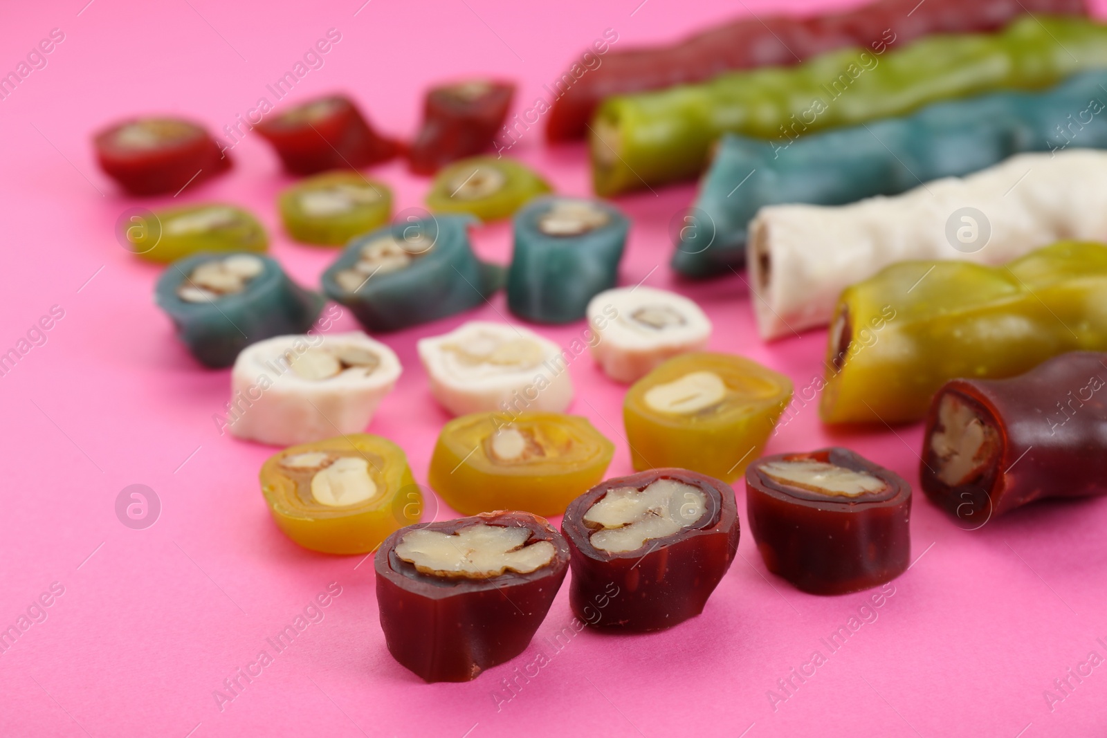 Photo of Many different delicious churchkhelas on pink background, closeup