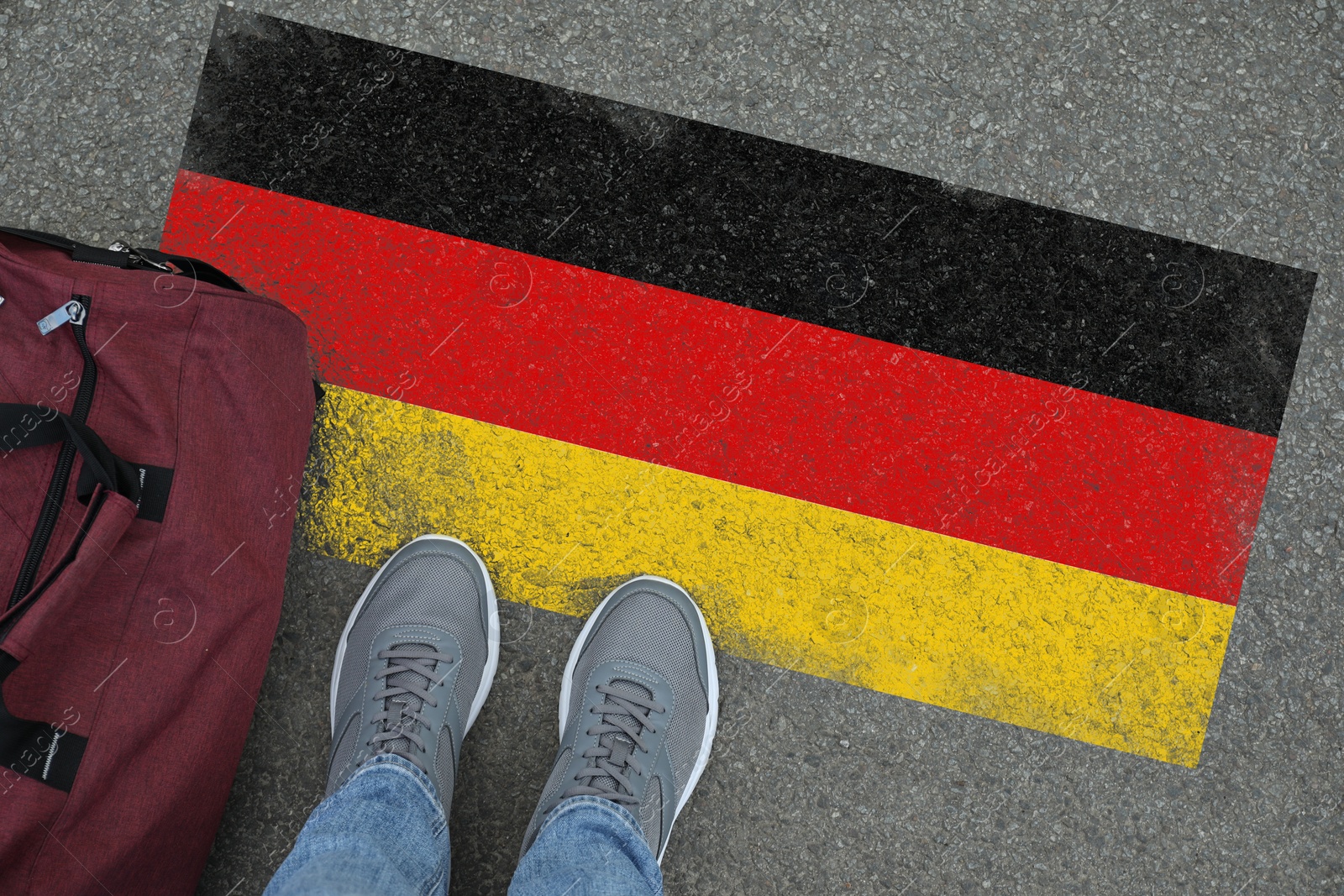 Image of Immigration. Man with bag standing on asphalt near flag of Germany, top view