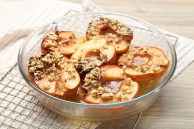 Delicious baked quinces with nuts and honey in bowl on wooden table, closeup