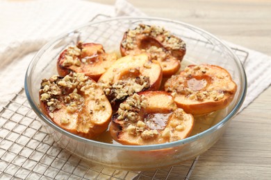 Photo of Delicious baked quinces with nuts and honey in bowl on wooden table, closeup